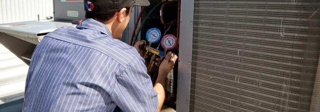 HVAC technician servicing a condenser unit in Fort Thomas